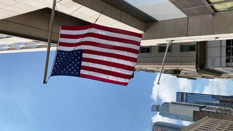 American national flags hang from the facade of a building in New York City. Lower Manhattan downtown skyscrapers. Financial and business district. Patriotism of USA.