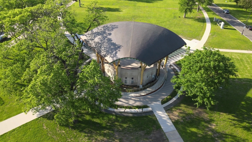 Birds eye view of covered structure in park in La Crosse, Wisconsin. Bright green foliage in the park. Designs in the bricks around the structure. Sun creating shadows on summer day.  