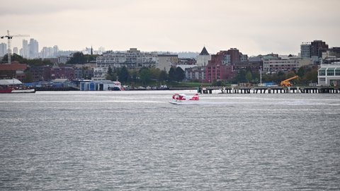 Vancouver, Canada - Oct 05 2019 : Commercial seaplane flying from coastline and industrial cargo port at Vancouver town