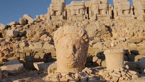 Antique statues on Nemrut mountain at sunrise in Turkey. Ancient stone head close-up at the top of 2150 meters high Mount Nemrut, Eastern Anatolia, Turkey. Slow steadicam footage