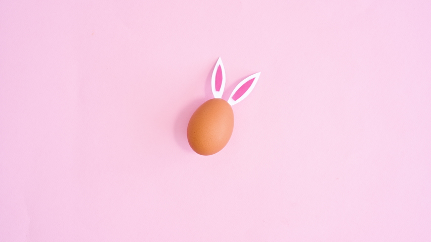 6k Creative Easter egg with rabbit ears appear and move on pastel pink background. Flat lay stop motion Royalty-Free Stock Footage #1087948257