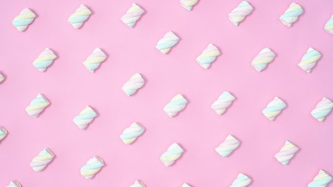 6k Creative sweet pattern with marshmallow candies moving on pastel pink background. Stop motion flat lay