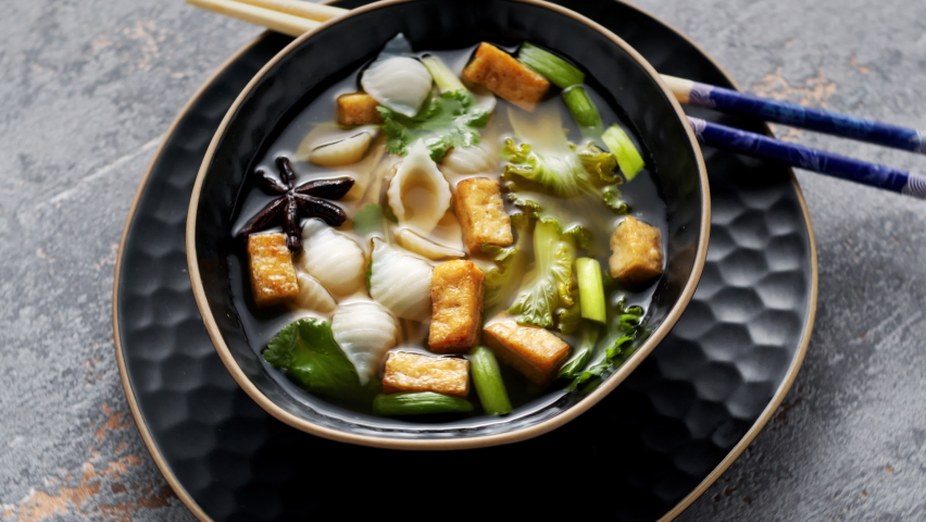 Pho soup with fried tofu cubes, noodles, pak choi and vegetables. Table spin, zoom-in. Royalty-Free Stock Footage #1087949023
