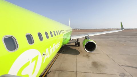Egypt, Sharm El Sheikh, 14 November 2021: The wing and body of bright green S7 airline aircraft in clear sunny weather, departure for travel, no people on the runway