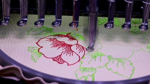 Machine embroidery on beige leather with red and green thread. Embroidery design with flowers up close. 4k video
