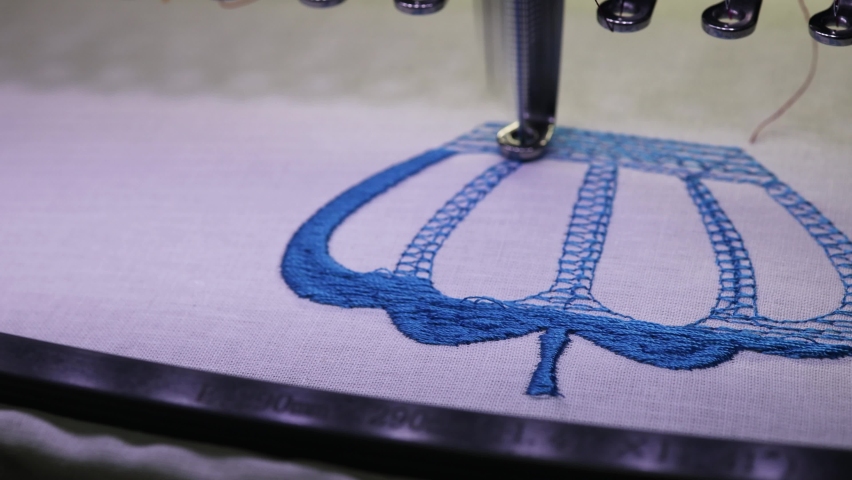 Machine embroidery of a crown on a cotton cloth with blue thread. Photo up close. 4k video.