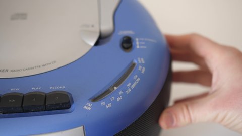 man tuning fm frequency on 2000s style radio with hand, closeup, shallow depth of field