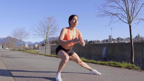 Attractive fit young woman doing side lunges exercising outdoors 