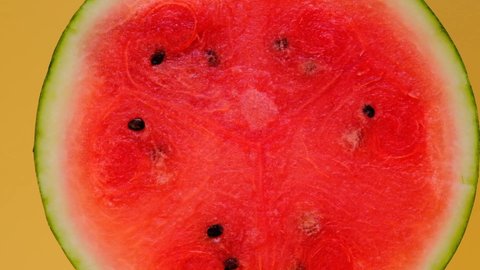 Watermelon in a cut on a yellow background.Rotation.Fresh ripe red watermelon half. Watermelon pulp close-up.Appetizing summer fruits. 4k footage