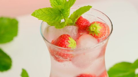 Mineral water with strawberries in a glass goblet.Strawberry drink. High quality 4k footage