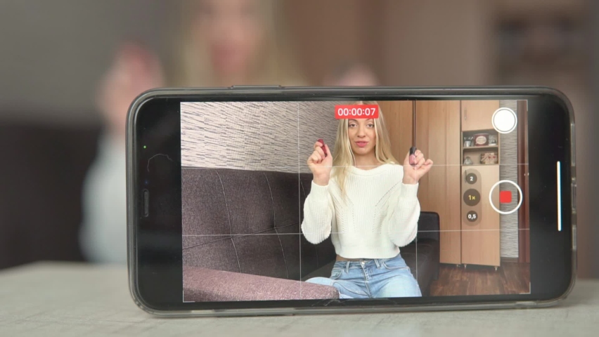 Young woman influencer, advertising and selling goods online in a live stream show. Creating video content for social media. Distant work at home studio. Beauty cosmetic shop girl recording video.