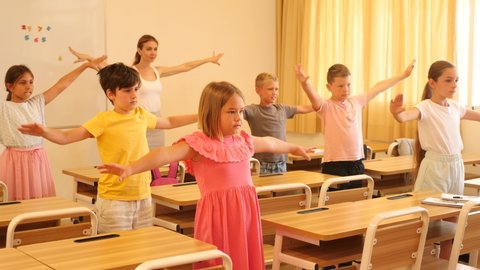 Schoolchildren doing warm-up exercises during their lesson in classroom.