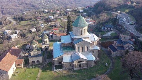 View from drone of restored ancient Gelati Monastery of Virgin on wooded hillside on sunny spring day. Religious and cultural landmarks of Georgia 