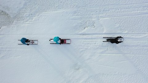 Three kicksleds riding on the ice filmed from above in the winter. The bird's eye view shot, or top down shot, was filmed with a drone.