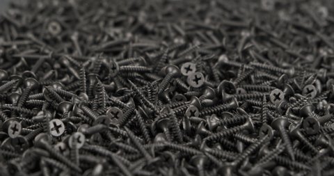 Close-up of a heap of black screws. Screws rotation. Industrial background