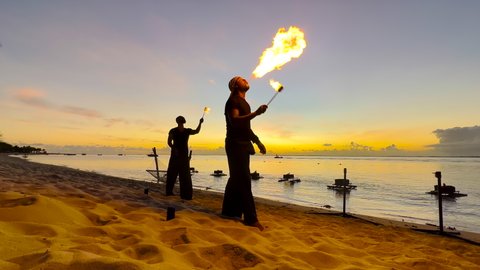 Cool fire show artist breathes fire in dark air, performing amazing stunts on the background of the ocean