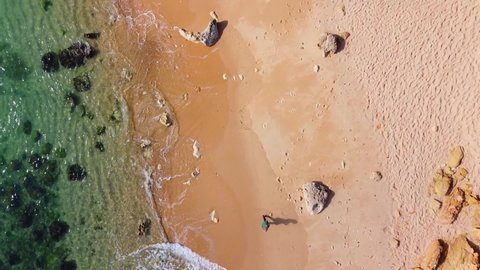 Top view over beautiful tropical beach. Aerial drone shot over calming beautiful waves. Clear water with golden sandy beach. Water surface texture. Beautiful sea waves. Tourism destination I