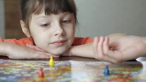 Happy child with board game. A happy child play with her mother with a boad game in the room.