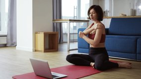 Woman practicing yoga with trainer via video conference, warming up joints