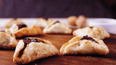 Purim cookies with poppy-seed filling triangular gomentashi rotate in a circle on a wooden board.