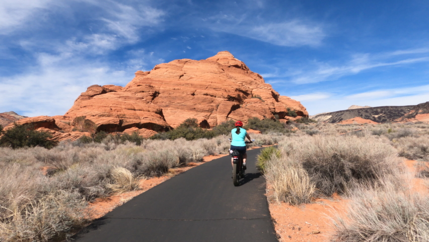 Woman Ride bike trail desert red rock landscape Utah. Bicycle trails in St George southern Utah in desert and red rock landscape. Healthy Exercise on paths in mountains. Royalty-Free Stock Footage #1087983445