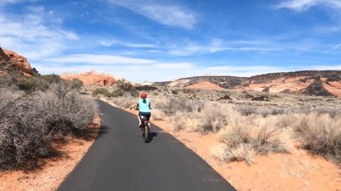 Woman Ride bike trail desert red rock landscape Utah. Bicycle trails in St George southern Utah in desert and red rock landscape. Healthy Exercise on paths in mountains.