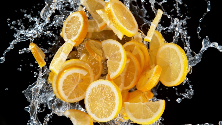 Super slow motion shot of rotating exploded lemon slices with splashing water on black at 1000fps.