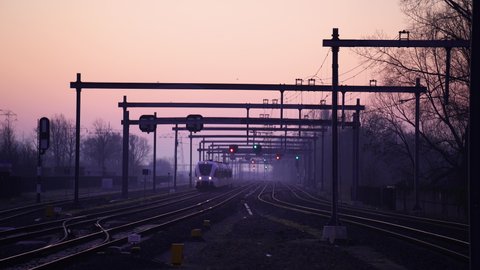 GRONINGEN, NETHERLANDS, March 3, 2022: A train riding on the tracks during a purple dawn.