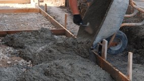 Workers pouring concrete on the ground and distributing it