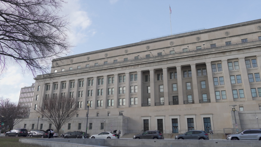 South entrance to the Stewart Lee Udall Building, headquarters of the United States Department of the Interior, located on C Street NW in downtown Washington, DC in winter. Left to right panning shot. Royalty-Free Stock Footage #1087986747