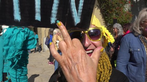 CALIFORNIA - CIRCA 2022 - a woman holds a peace sign at a Ukranian antiwar rally, and turns it to say Puck Futin (fuck putin).