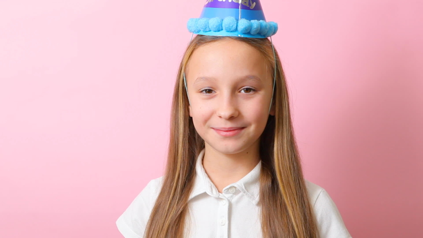a teenage girl in a festive cap blows a tune. Birthday concept