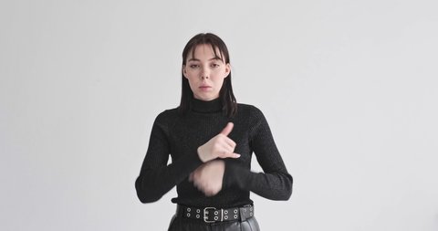 young girl in black clothes on white background waving her hands shows something using sign language