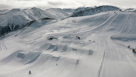 Livigno, Italy - February 21, 2022: People snowboarding and skiing at ski resort. Skiers and snowboarders riding snowy mountain slope. Outdoor winter sport. Winter mountain landscape. Aerial footage 