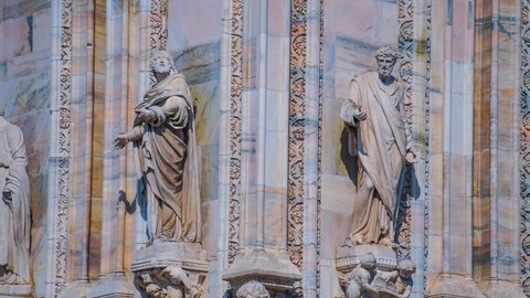 Decoration at the Gothic Cathedral of Milan. Statues and bas-reliefs. Piazza del Duomo before sunset. Blue sky over the temple. Architettura and details closeup. Sculptures, statues style in details