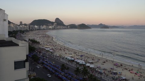 Rio de Janeiro, Brazil - February 28, 2022 - aerial sunset static view of people and cars on Copacabana Beach