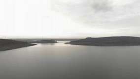 Aerial footage over the waters of a reservoir about 20 meters high. The camera moves towards the distant shores on the horizon.