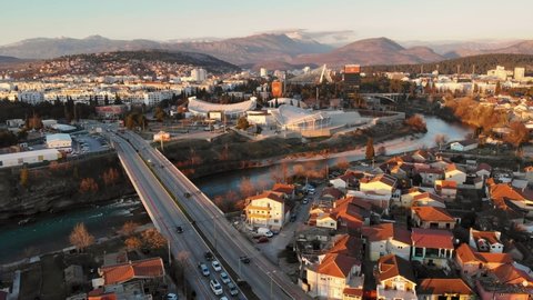Podgorica , Montenegro - 01 26 2022: Drone flying across the Moraca, Union Bridge crossing the River in Podgorica Montenegro during sunset, Cityscape in background
