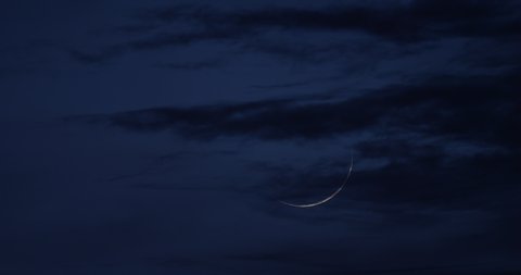 New Moon, a 2% crescent, with drifting clouds at twilight.