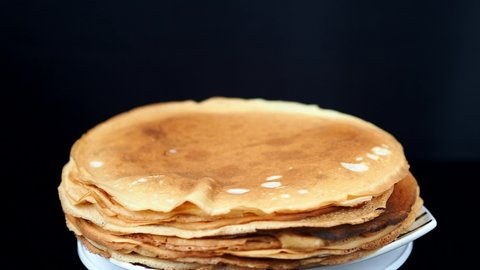 Pancakes on a spinning plate. Black background. Maslenitsa holiday. High quality 4k footage