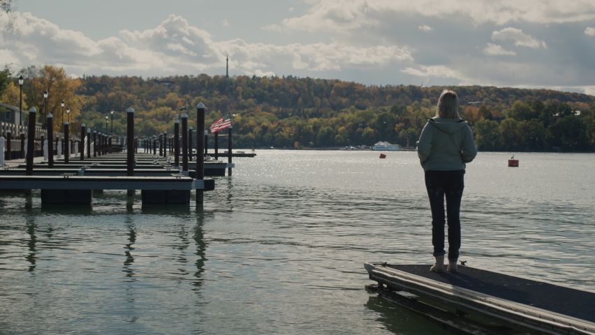 The village of a woman stands on the pier and admires Lake Ontaria at the end of the tourist season.