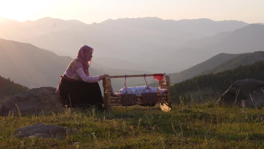 peasant woman putting her baby to sleep in the old wooden cradle (selective focus).Turkey Royalty-Free Stock Footage #1087997227