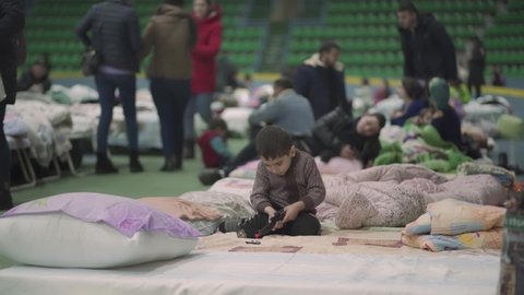 chisinau, moldova - march 4 2022: ukranian refugee boy plays with toy gun at the chisinau arena refugee center