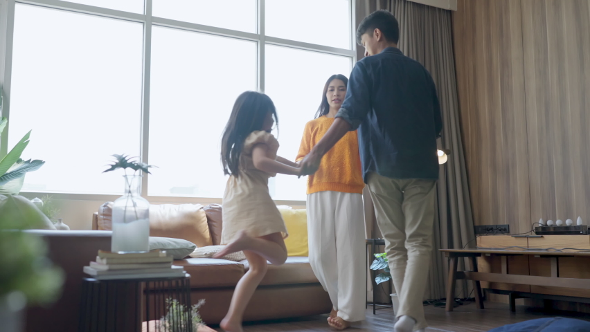 happiness sunday morning dad mom and daughter spending wonderful moment dancing along together,asian family father mother and daughter jump dance cheerful moving together in living room at home Royalty-Free Stock Footage #1087998661