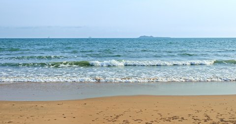 White foam of rolling waves in Sanya, Hainan Island, China. Beautiful seascape. Yellow sand beach, azure sea and blue sky.