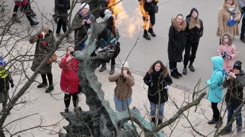 KRAKOW, POLAND - MARCH 6, 2022: Tourists looking up at legendary fire breathing Wawel Dragon Statue (Smok Wawelski). Sculpture by Bronisław Chromy, Wawel Hill in Kraków.