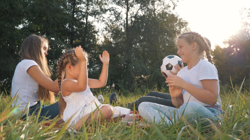 A group of children play ball, sit on the grass. Family sports games for fun. Happy cheerful family enjoying a trip together. Family in the garden park.