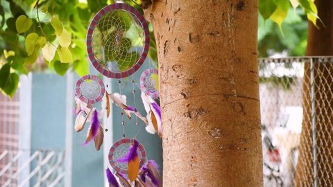 Close up of dream catcher on background of tree leaves with vibrant tone. Hand made. Dreamcatcher feathers flowing in wind. Decoration of home