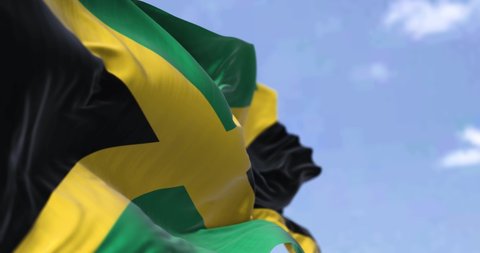Detail of the national flag of Jamaica waving in the wind on a clear day. Jamaica is an island country situated in the Caribbean Sea. Selective focus. Seamless loop in slow motion