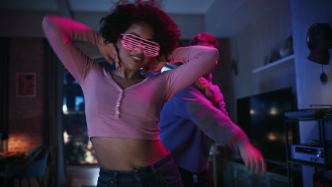 Close Up Portrait of Diverse Multiethnic Couple in Casual Clothes and Futuristic Neon Glowing Glasses, Dance and Have a Party at Home in Loft Apartment. Recording Funny Viral Videos for Social Media.